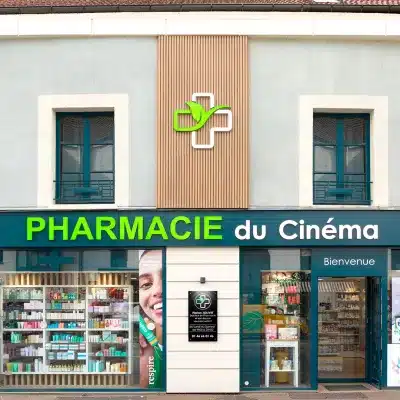 Vue d'ensemble de la Pharmacie du Cinéma, montrant l'enseigne lumineuse et la façade rénovée.